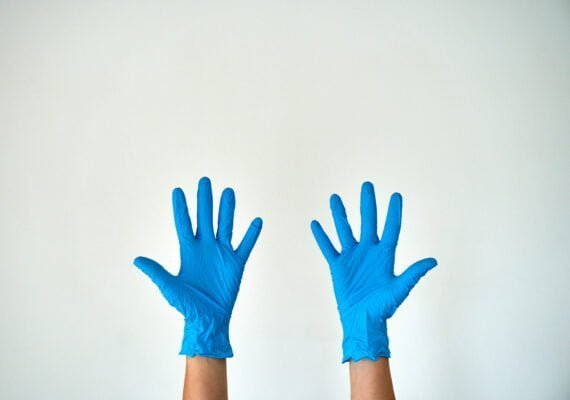 Two hands preparing to wear Disposable Blue Nitrile Gloves - Medical Grade, Latex & Powder-Free for enhanced protection.